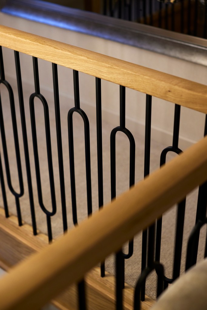 Detailed close-up of a smooth oak handrail and modern black iron spindle balustrades in a Denshaw home.