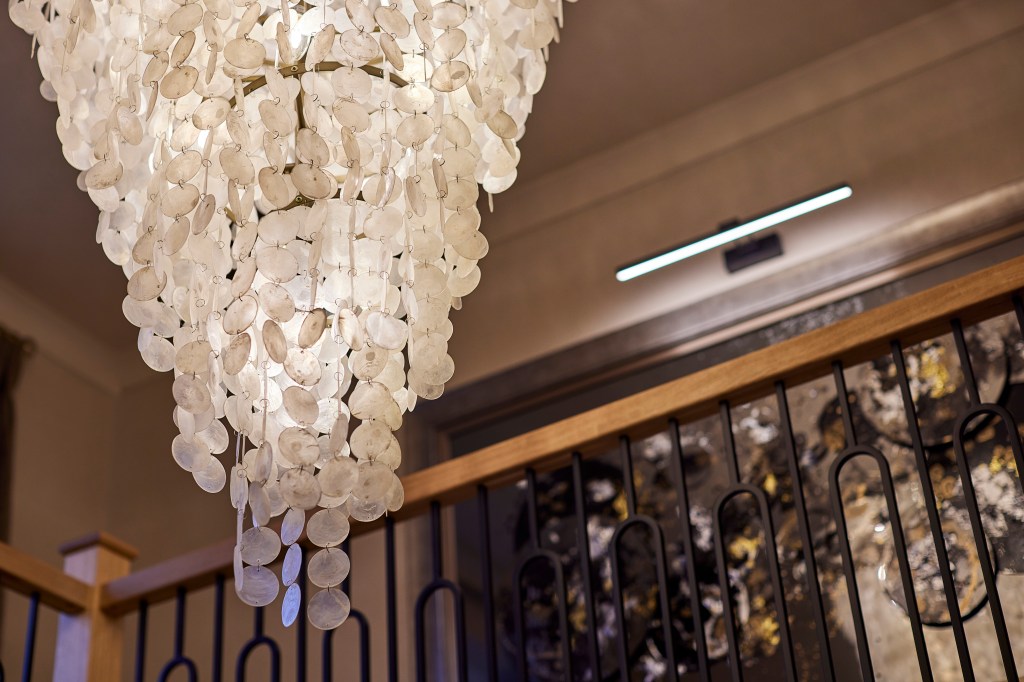 Oversized capiz shell chandelier hanging above an oak and iron staircase in a Denshaw home designed by Galatea Studio.